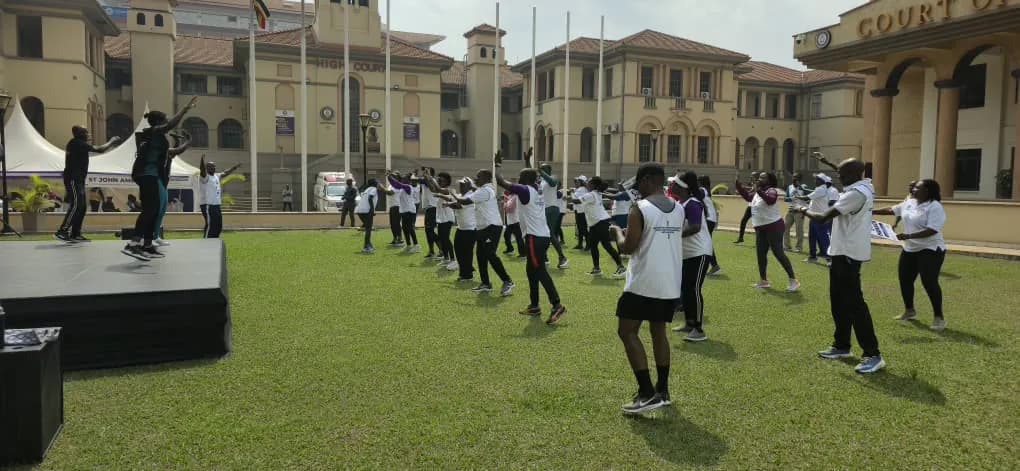 A large group of judicial staff taking part in a wellness session on the grounds of the High Court of Uganda